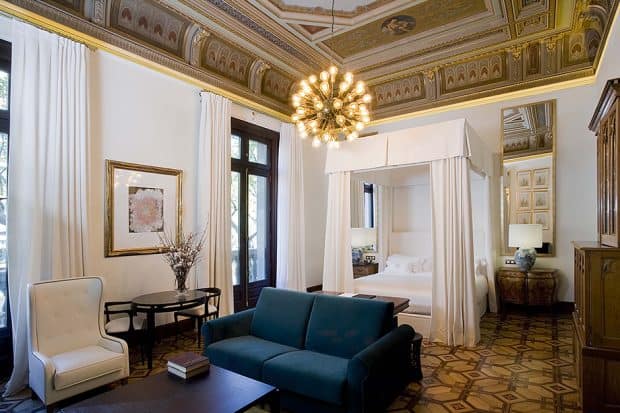 Bedroom with white canopied bed and blue couch at Cotton House, Barcelona